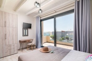 A bedroom with a bed, a desk, a chair, a television, and a large window. - Elmara Lux Seaside Villa 1 Private Pool in Crete (Faistos)