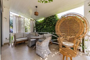 An outdoor seating area with wicker furniture, a white cushioned sofa, and a round wicker chair. - Holiday Villa | Patio & Free Parking by PikHost (Dhërmi)