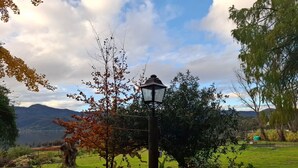 Un jardin avec un lampadaire, des arbres et une chaîne de montagnes lointaine.