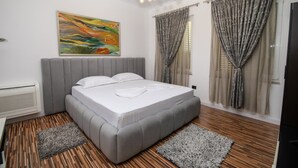 A bedroom with a bed, a radiator, a painting, and curtains. - Private Luxury Villa with Pool, River Views (Shkodër)