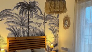 Een slaapkamer met een bed, wanddecoratie, een hanglamp en een raam met gordijnen.