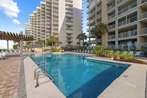 A swimming pool with lounge chairs and a pergola, surrounded by tall residential buildings. - White Caps 505 by Liquid Life (Orange Beach)