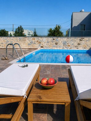 Ein Pool auf dem Dach mit Liegestühlen und einer Obstschale.