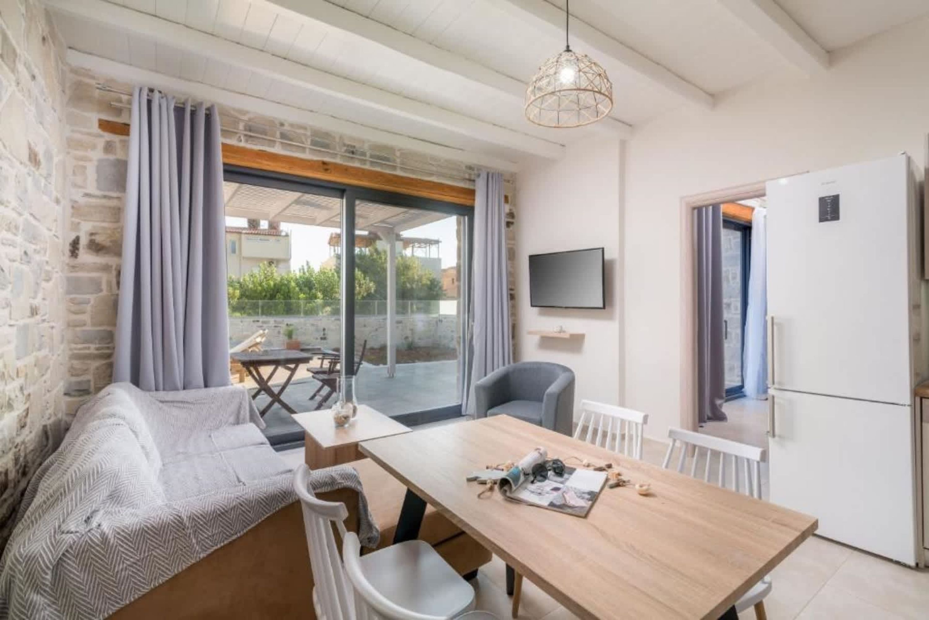 A modern room with a wooden table, a sofa, a TV, and a refrigerator.