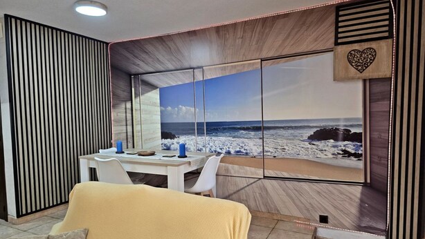 Una habitación con un ventanal grande con vistas al océano, un comedor y un área de estar con una vista.