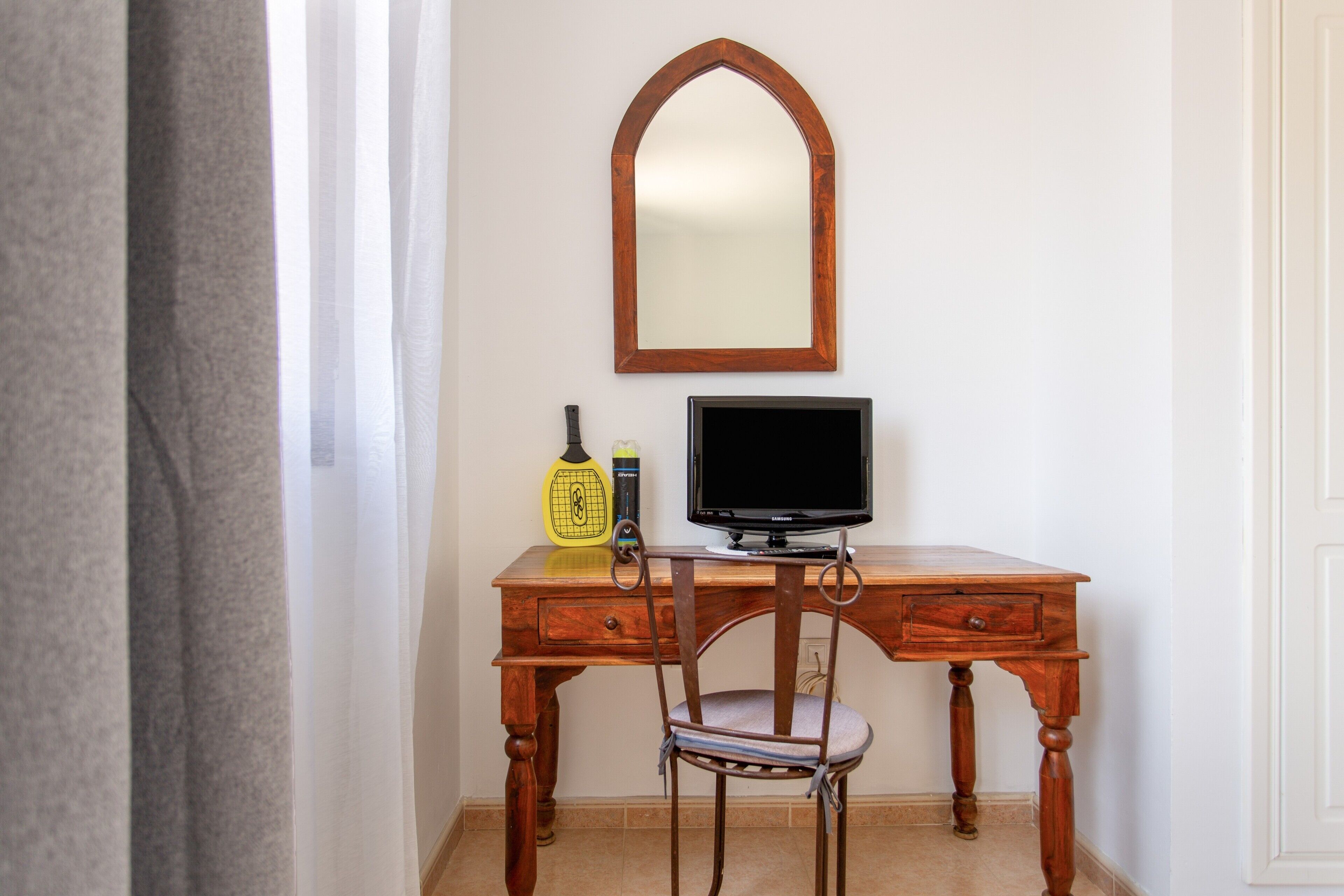 Een houten bureau met een televisie, een spiegel en een stoel.