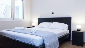 A modern hotel room with a large bed, bedside tables, and a view of the outside. - Urban 2 Bd Home in Vibrant Galatsi (Galatsi)