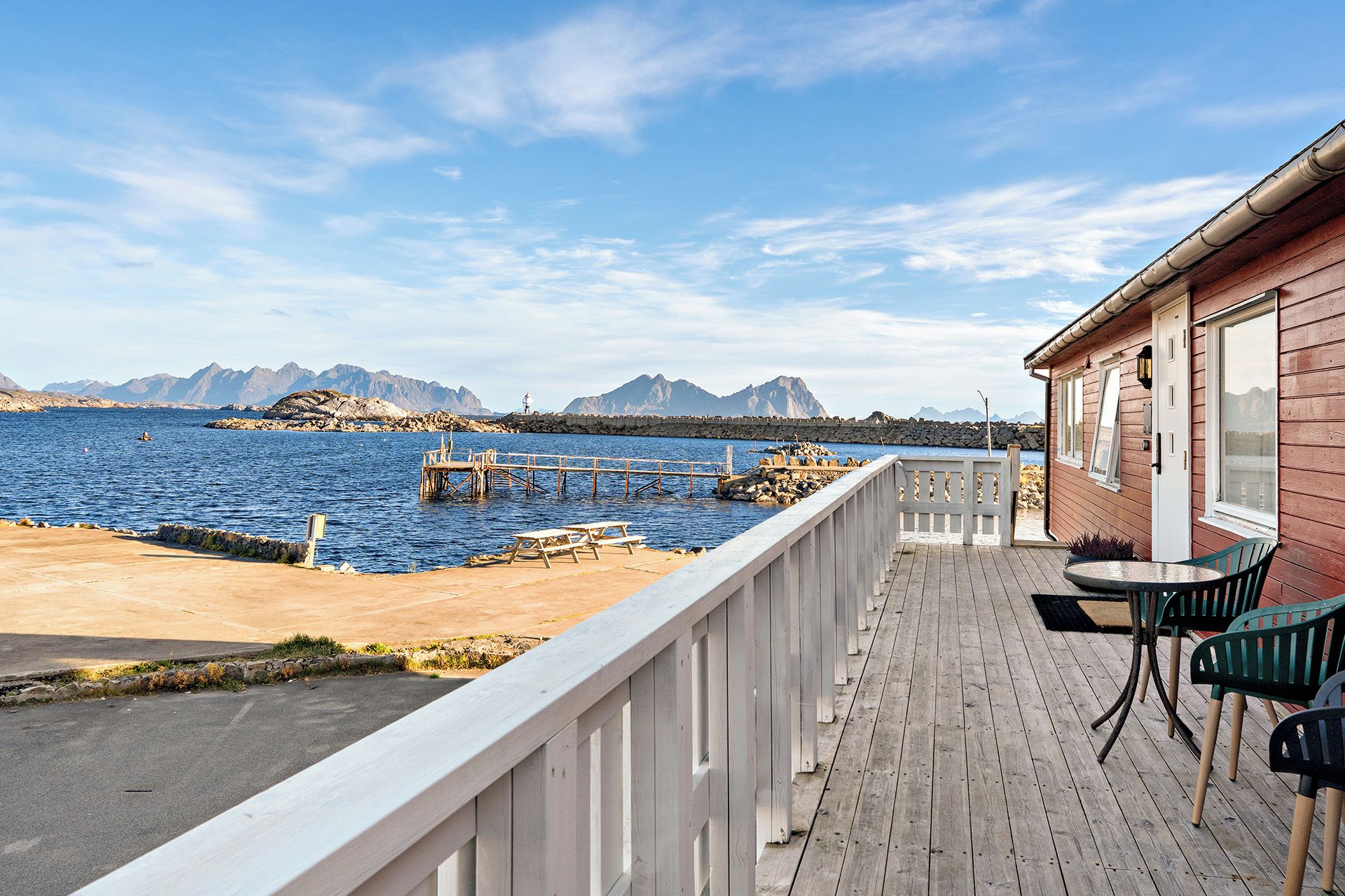 A wooden deck with a view of the sea and mountains.