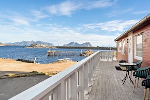 A wooden deck with a view of the sea and mountains. - Astra Whale - Waterfront Boutique Hostel in Lofoten (Vagan)