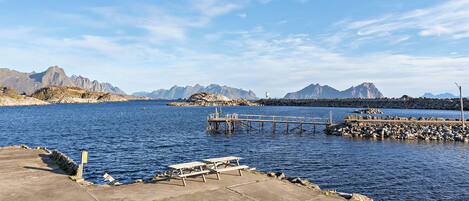 A coastal pier with a picnic table and a lighthouse in the background.