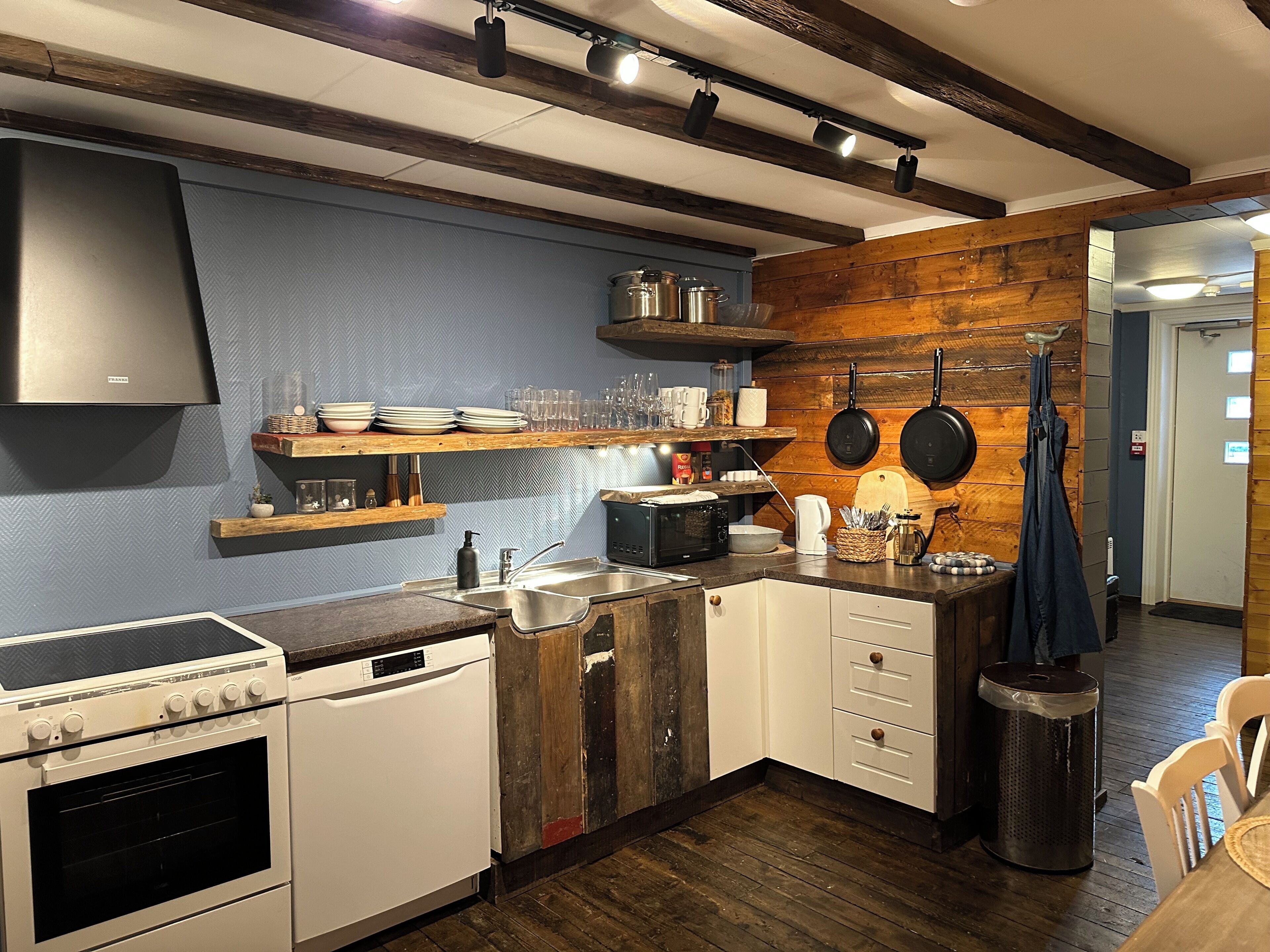 A compact kitchen with a stove, dishwasher, and wooden accents.