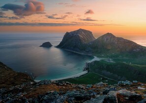 A coastal landscape with mountains, a body of water, and a road leading through a valley.