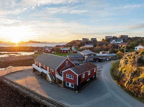 A coastal village with traditional red houses, a paved road, and a view of the sea. - Astra Whale - Waterfront Boutique Hostel in Lofoten (Vagan)