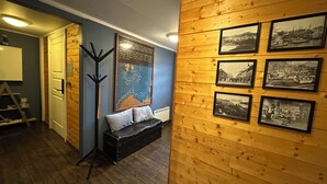 Una habitación con paneles de madera, un banco negro, un perchero y fotografías históricas enmarcadas en la pared.