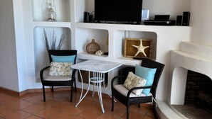 A living room with a TV, two chairs, a small table, and a fireplace. - Paradise Villa #5 | Oceanfront Escape at Playa Encanto (Puerto Peñasco)