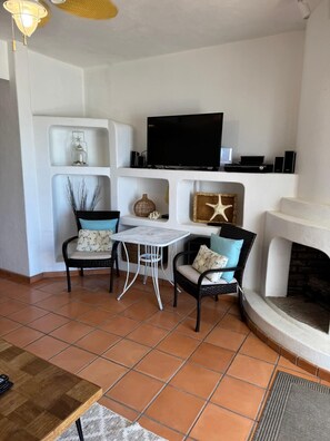 A living room with a TV, two chairs, a small table, and a fireplace. - Paradise Villa #5 | Oceanfront Escape at Playa Encanto (Puerto Peñasco)