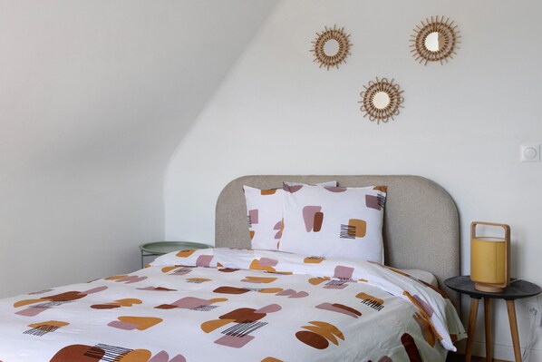 A bedroom with a bed, a bedside table with a lamp, and wall decor.