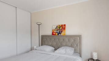 Ein Schlafzimmer mit einem Bett, einem Nachttisch, einer Stehlampe und einem Gemälde an der Wand.