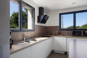 A modern kitchen with a large window, a built-in microwave, and a stainless steel sink.