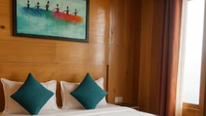 Una habitación con paneles de madera, una cama, almohadas, una alfombra y un cuadro en la pared.