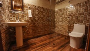 Un baño con piso de madera, un lavamanos, un inodoro y una zona de ducha.