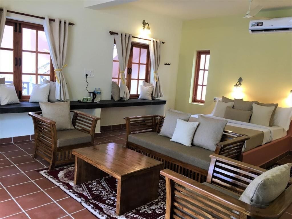 A room with a sofa, chairs, a coffee table, and a window with curtains.