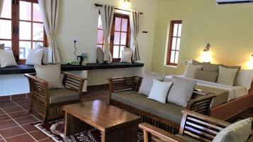 A room with a sofa, chairs, a coffee table, and a window with curtains.