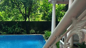 A swimming pool with ornate white railings and lush greenery in the background.