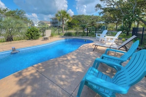 Une piscine avec des chaises longues et une clôture.