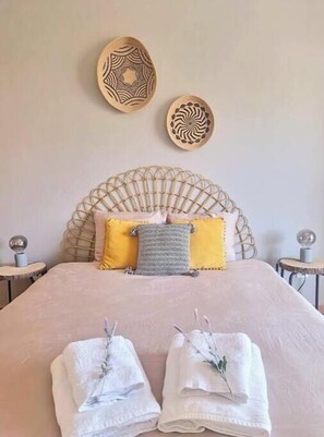 A neatly made bed with two towels, a headboard, and two wall decorations. - Boho Guesthouse Portimão | A Slow Living Escape (Portimão)