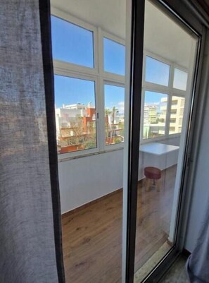 A room with a large window, wooden flooring, and a small stool. - Boho Guesthouse Portimão | A Slow Living Escape (Portimão)