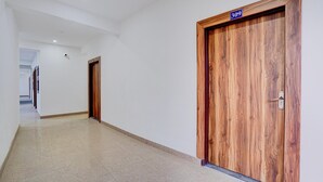 A corridor with two wooden doors, one marked with the number 309, and a tiled floor. - Classic Hotel Sky (Gurugram)