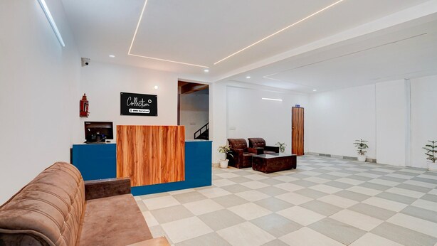 A reception area with a blue counter, a wooden accent wall, a brown sofa, and a checkered floor. - Classic Hotel Sky (Gurugram)