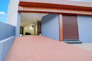 A modern building entrance with a red-tiled pathway leading to a wooden door. - Classic Hotel Sky (Gurugram)