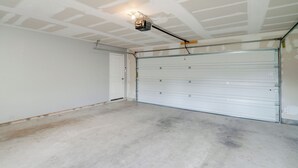 En garage med lukket garageport, en loftlampe og en betongulv.