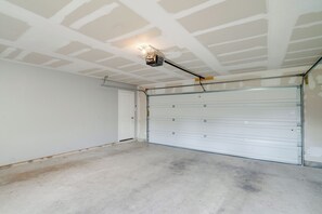 A garage with a closed garage door, a ceiling light fixture, and a concrete floor. - 8 Mi to Dtwn! Extended Stay in San Antonio w/ Yard (San Antonio)