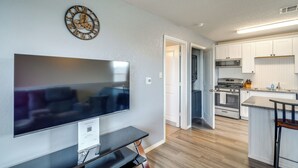 Et moderne køkken med hvide skabe, en stålkomfur og et fladskærms-tv monteret på væggen.