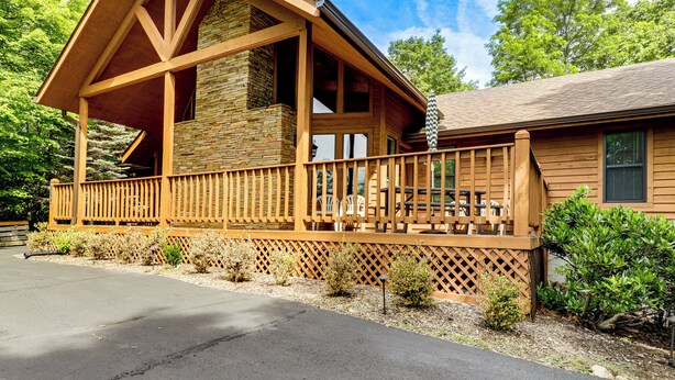 Een houten chalet met een veranda, stenen muren en een omheind terras.