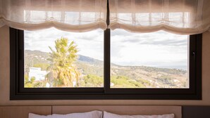 Ein Bett mit weißer Bettwäsche, ein Fenster mit Landschaftsblick und ein Vorhang.