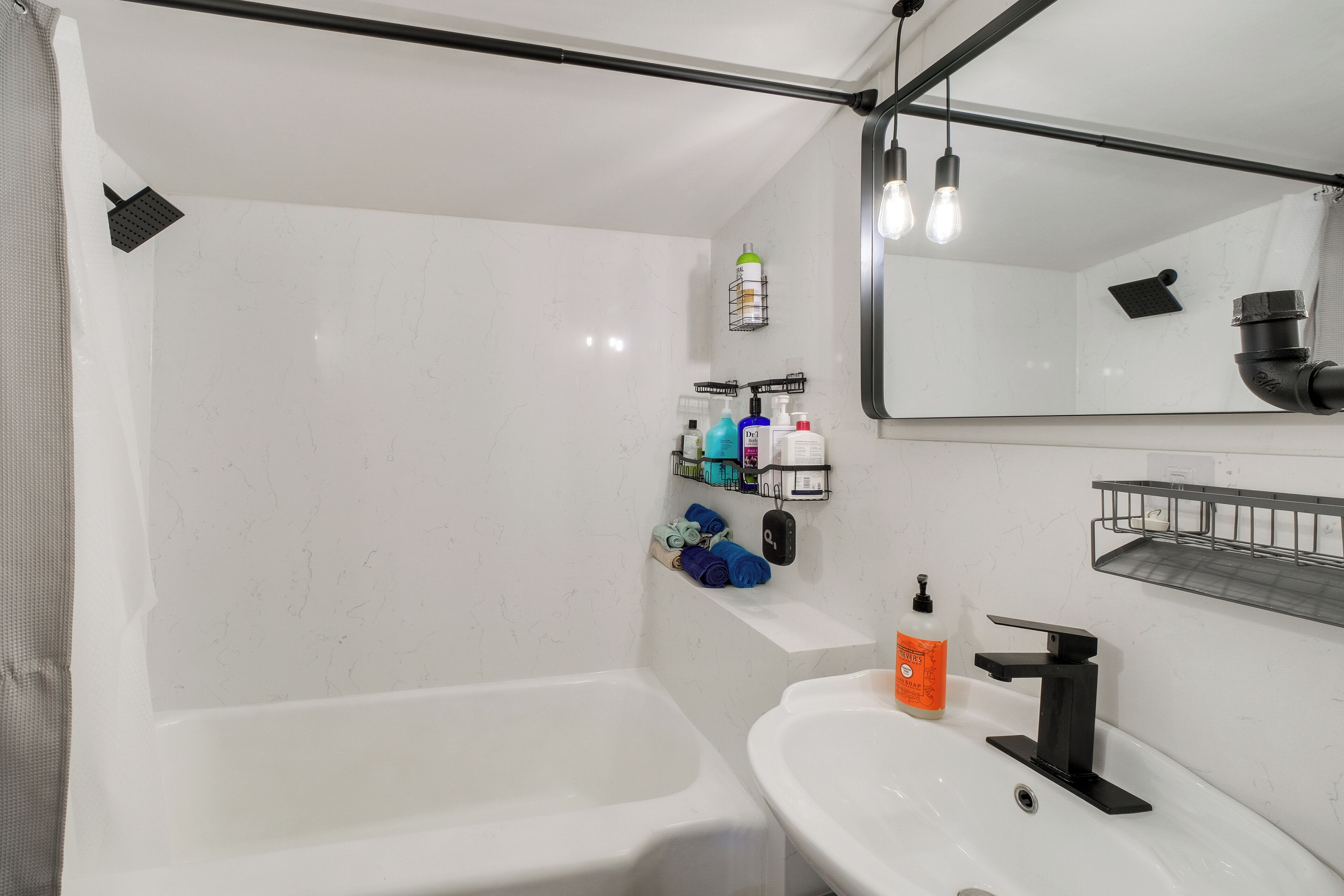 A modern bathroom with a bathtub, a sink, a mirror, and a showerhead.