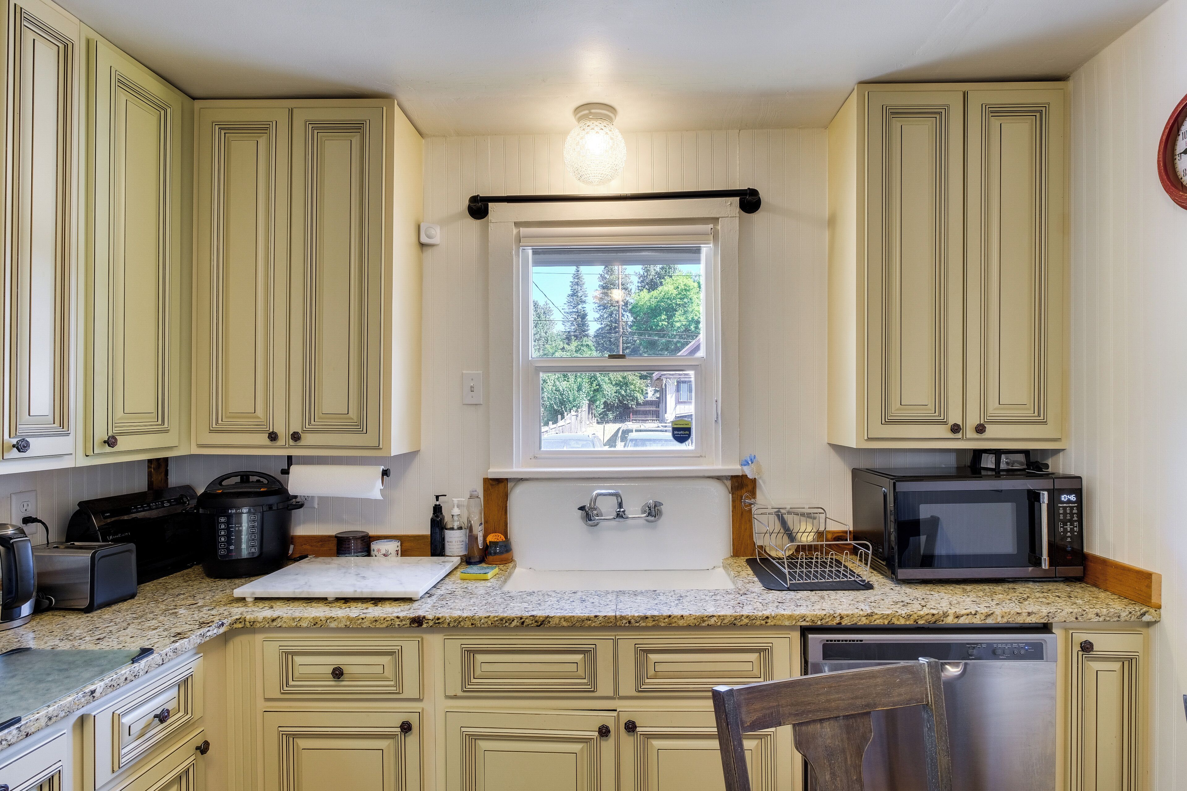A kitchen with a window, a microwave, a toaster, and a sink.