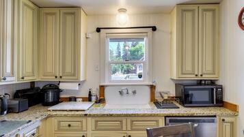 A kitchen with a window, a microwave, a toaster, and a sink.