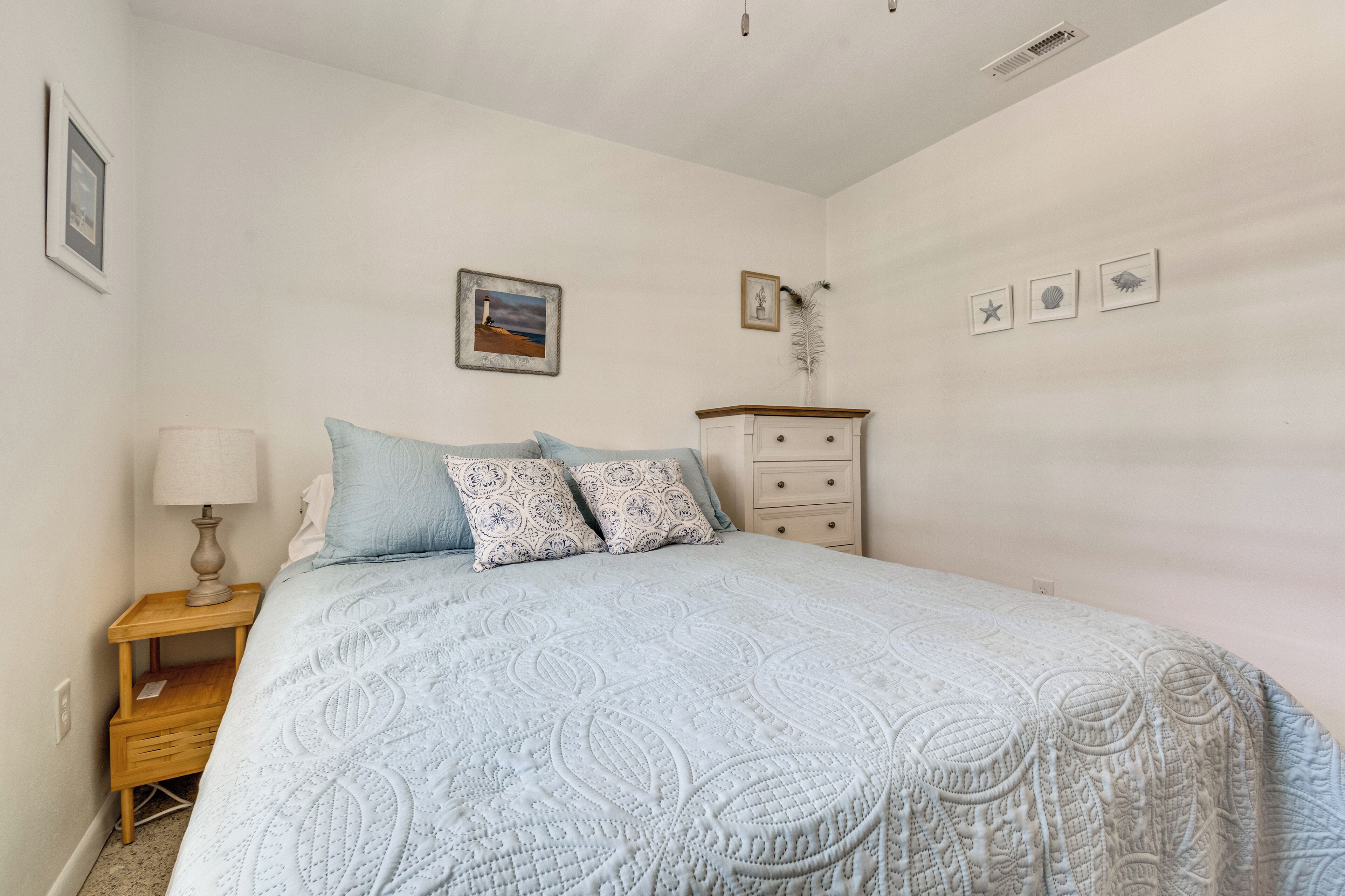 A bedroom with a bed, a nightstand, a dresser, and wall decorations.