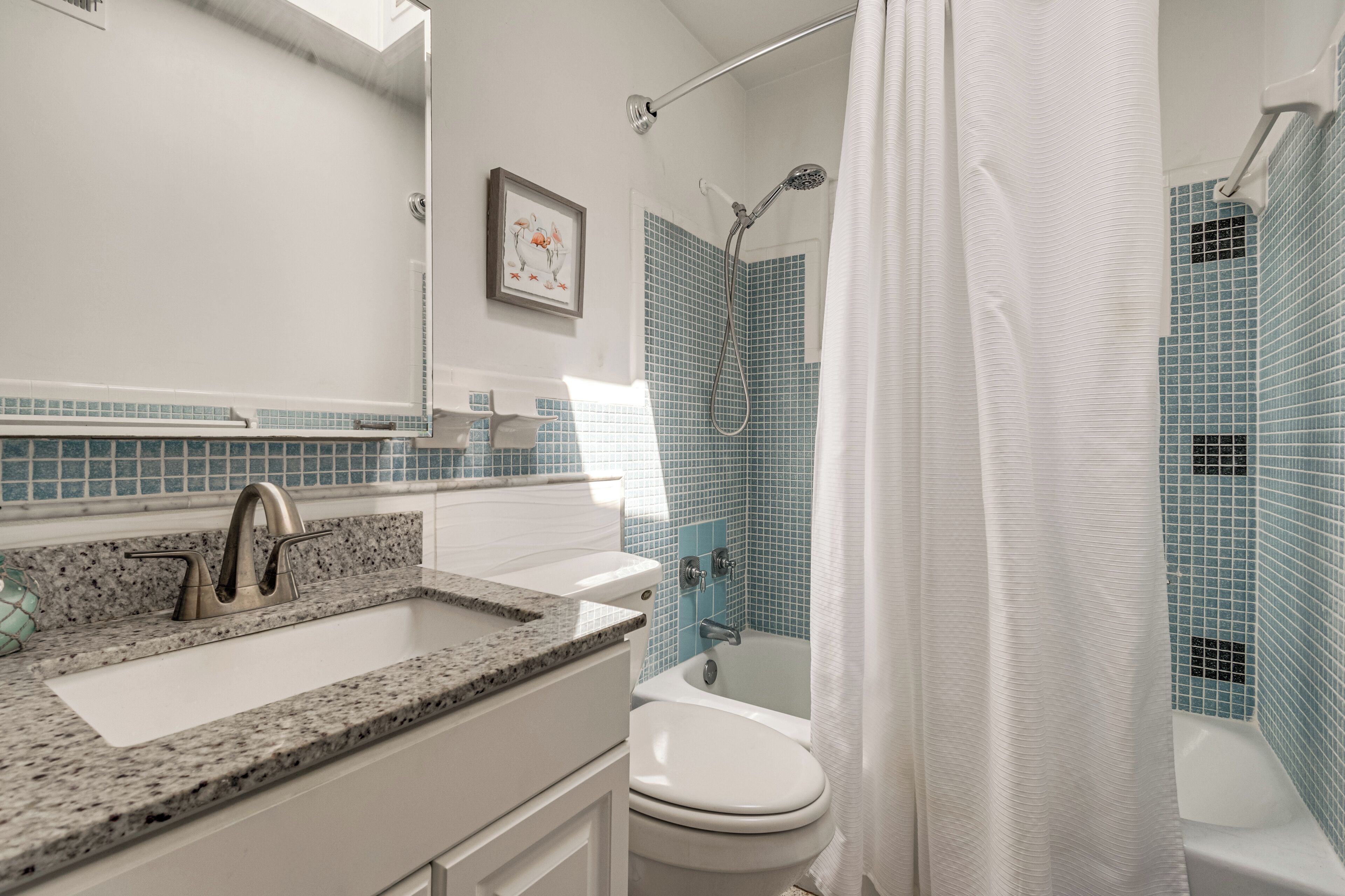 A bathroom with a sink, mirror, shower, and toilet.