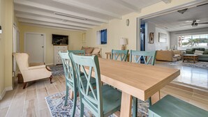 Ein Essbereich mit einem Holztisch und -stühlen, einem gemusterten Teppich und Blick in das Wohnzimmer.