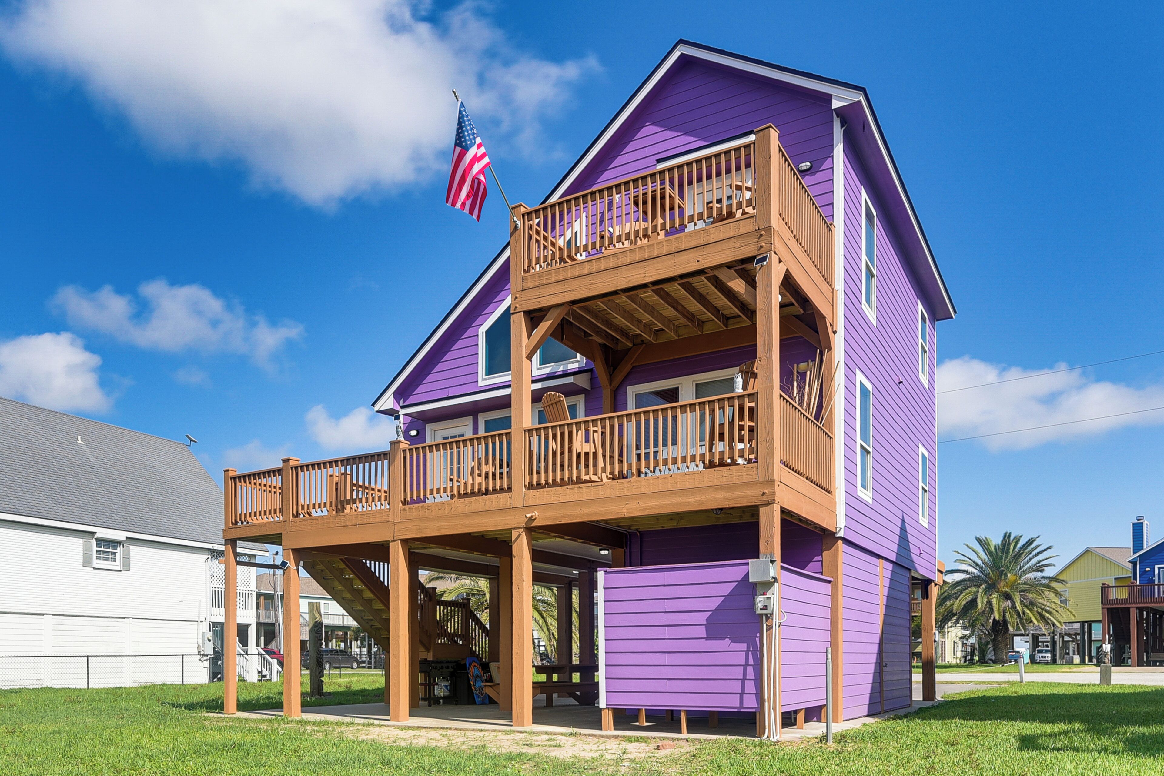 A two-story building with a wooden deck and a balcony, featuring a flag.