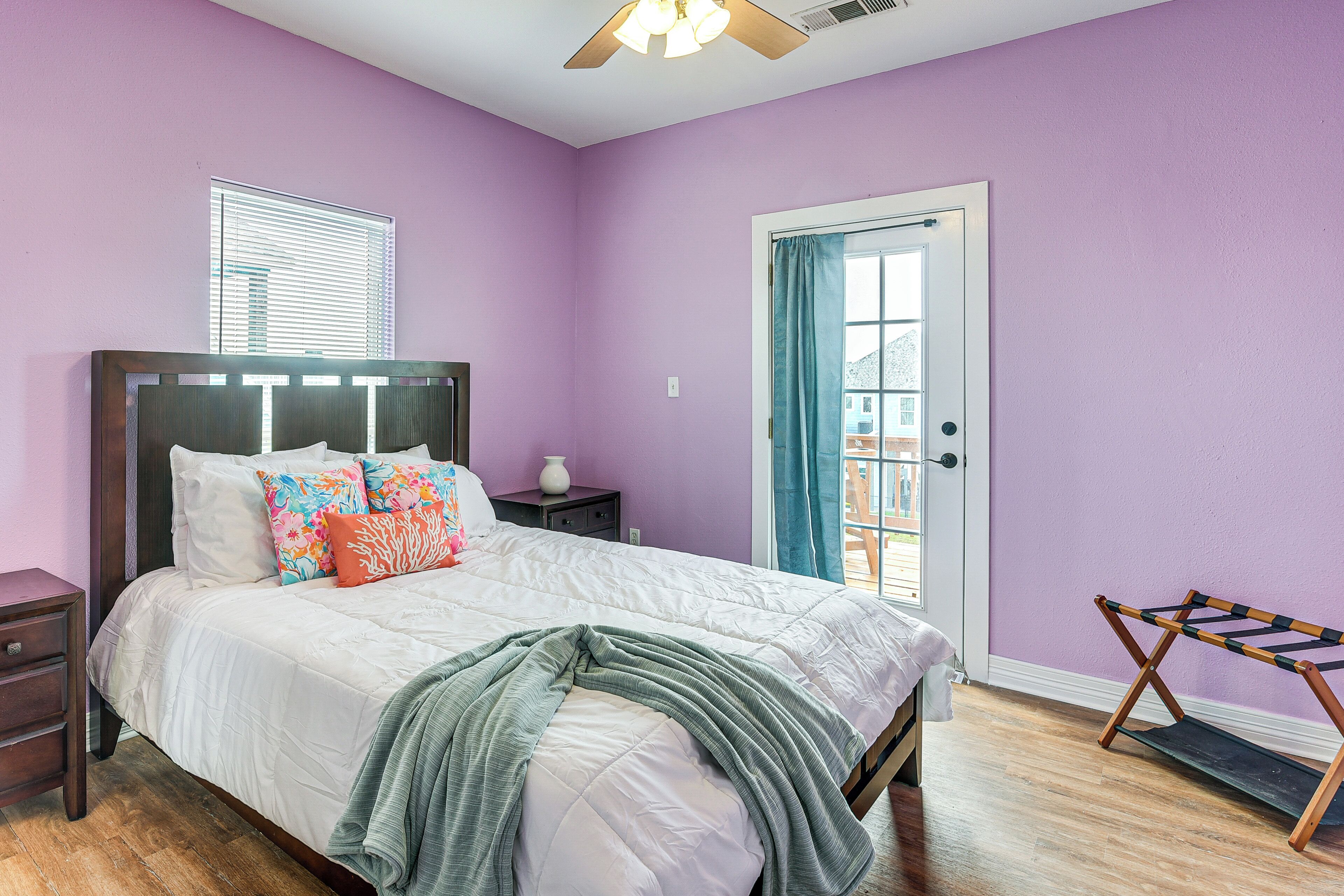 A bedroom with a bed, nightstand, dresser, and a window with blinds.