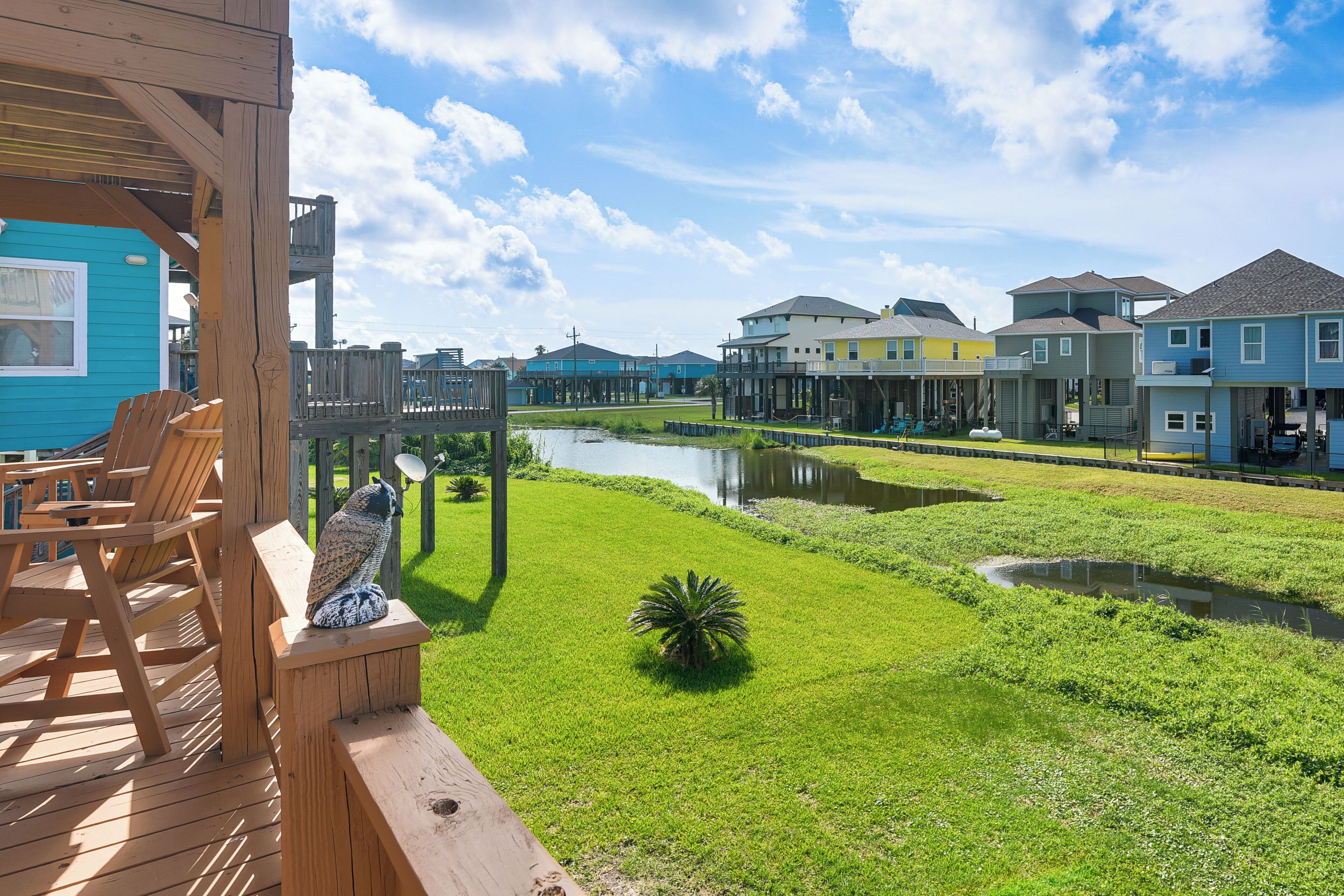 A waterfront property with a wooden deck, outdoor seating, and a small pond.