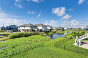 A waterfront residential area with houses, a small pond, and a pedestrian bridge.