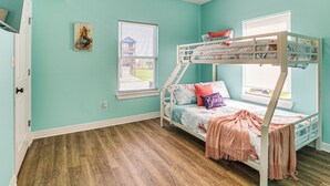 Una cama litera con ventana, ventilador de techo y una puerta.